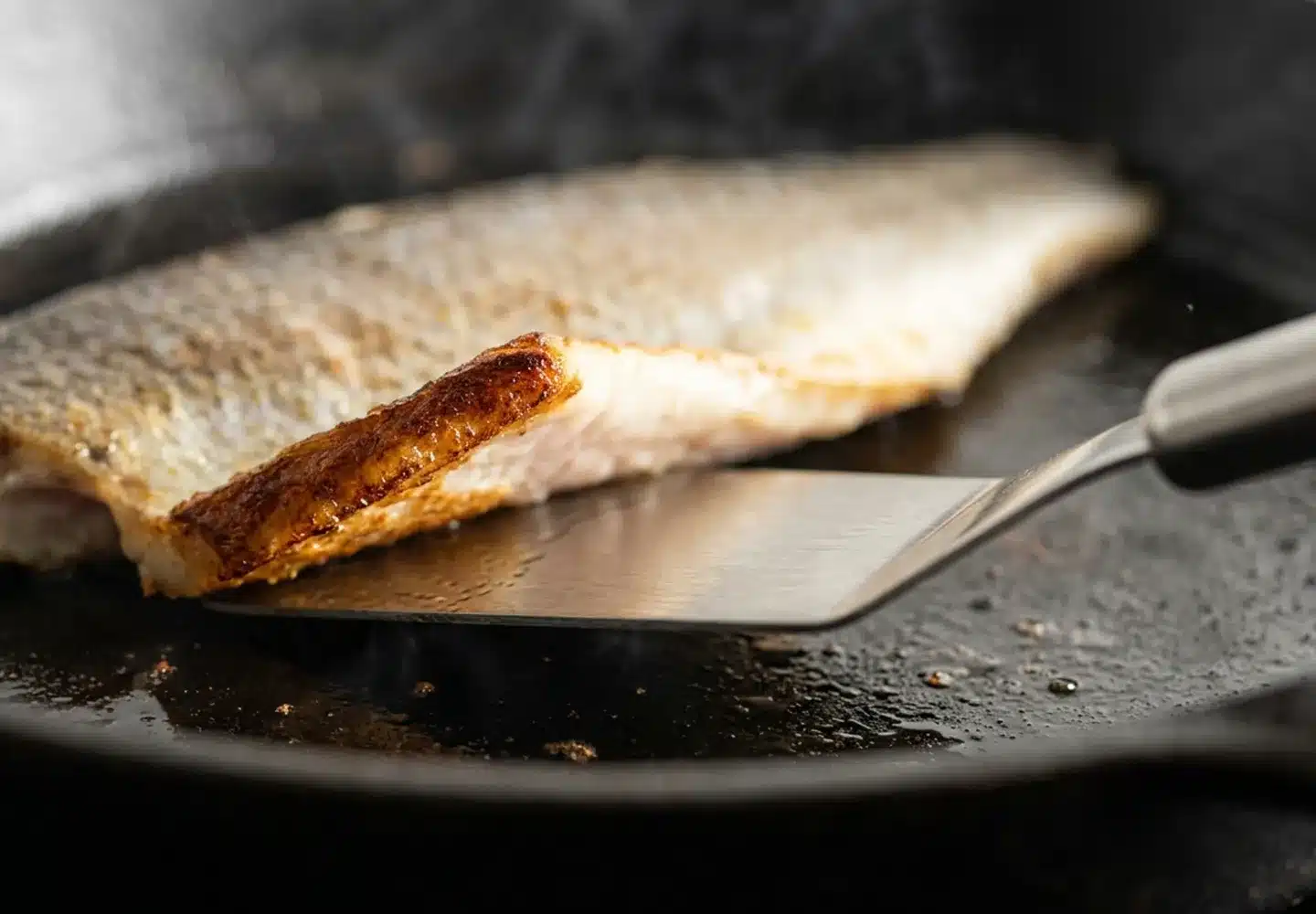 lifting fish in a pan with spatula